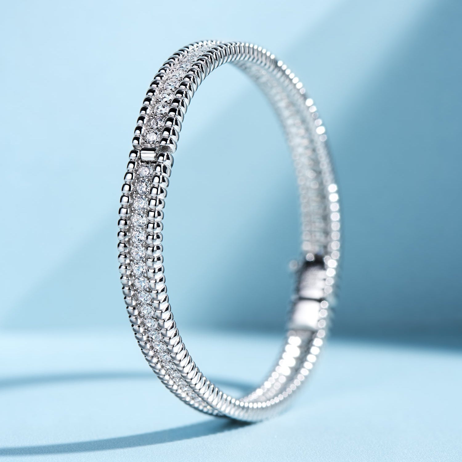 A two-tone, silver and gold-colored bracelet with a thick layer of gold or rhodium plating, featuring a row of stones.