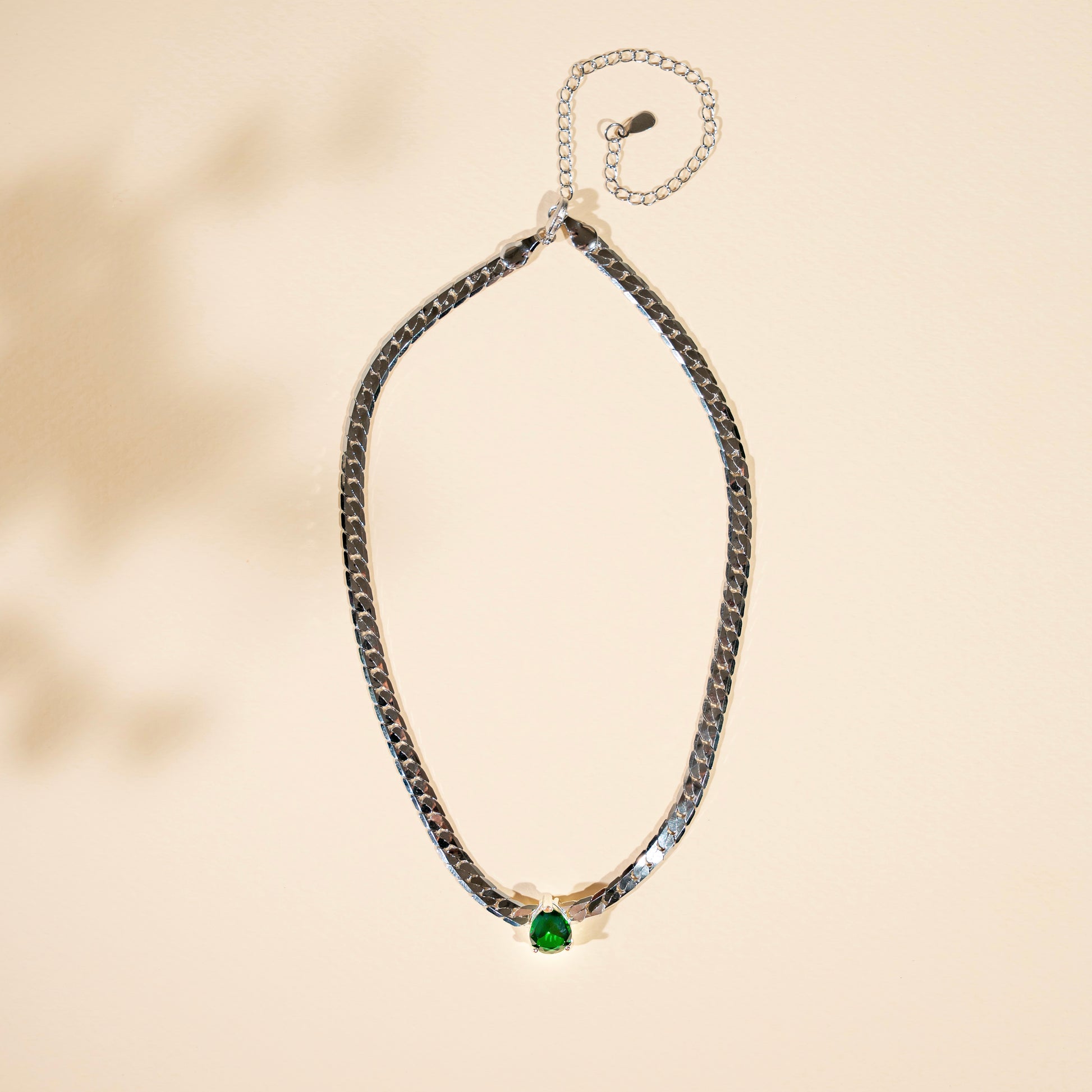 Necklace with a green gemstone on a beige background