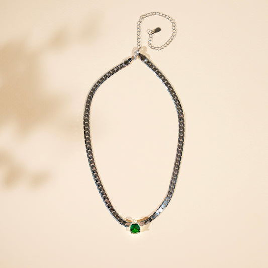 Necklace with a green gemstone on a beige background