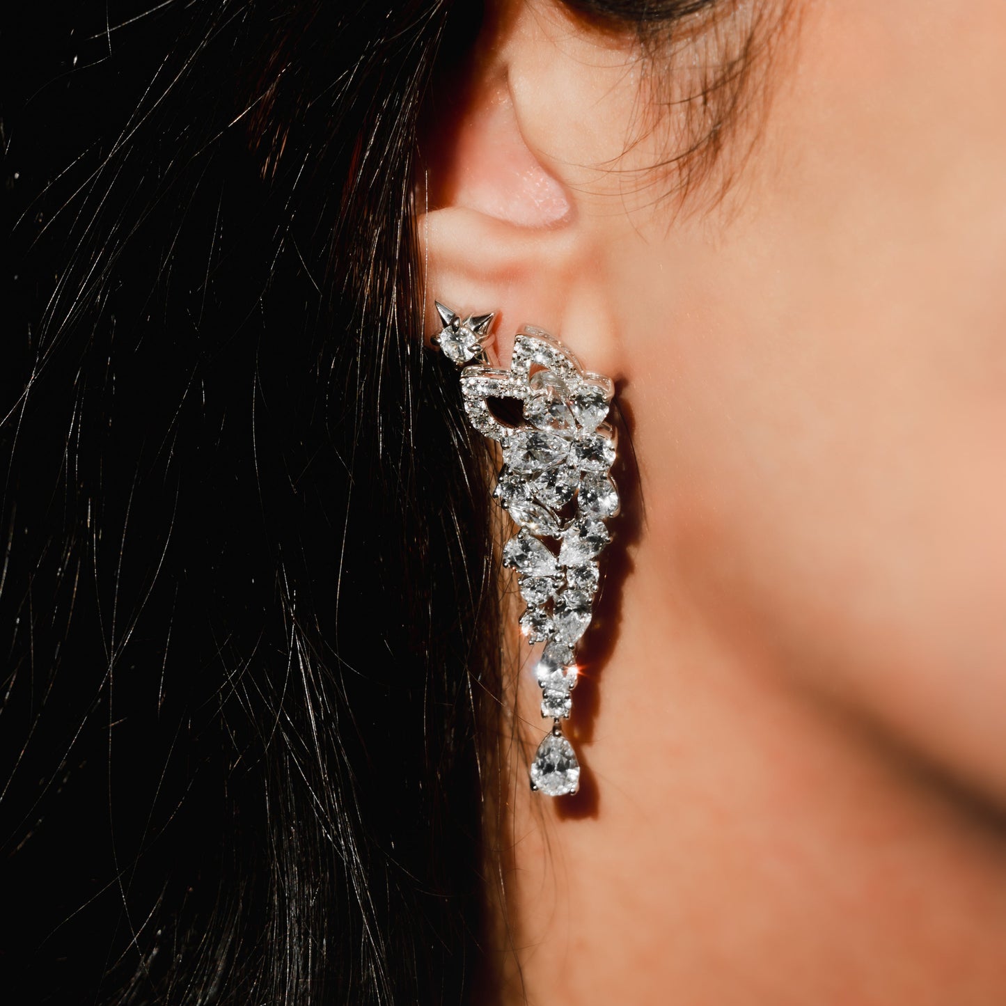 Close-up of a person wearing a sparkling diamond earring.